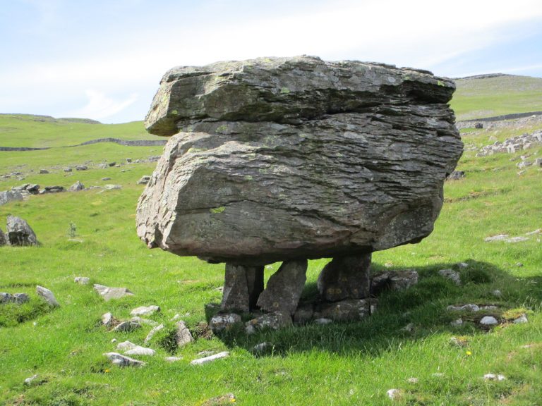 A stone resting on several much smaller stones which appears to be a natural phenomenon.